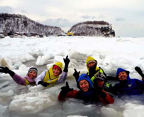 Para wisatawan yang mengenakan drysuit berenang di perairan laut es di Shari, Hokkaido, pada tanggal 8 Februari (Masatoshi Narayama)