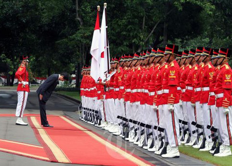 Japanese Prime Minister Shinzo Abe pays tribute to Indonesian and Japanese flags at the State Palace in Jakarta on Jan. 18, 2013